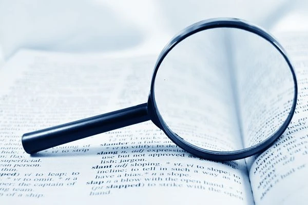 A magnifying glass lays on an open book.
